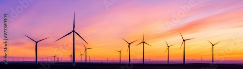 Scenic view of wind turbines at sunset, showcasing renewable energy in a vibrant sky filled with hues of orange and purple.