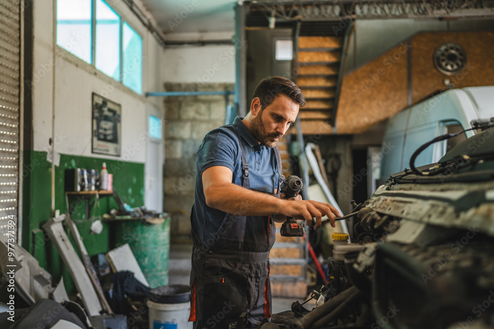 Car mechanic work on vehicle with drill tool in repair garage shop Car mechanic work on vehicle with drill tool in repair garage shop