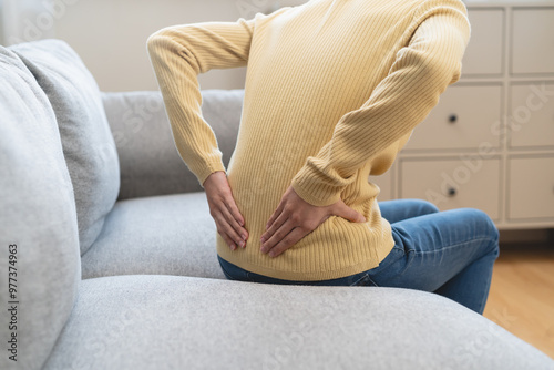 Close-up woman massaging her lower back has back pain because of sitting posture during work in office. photo