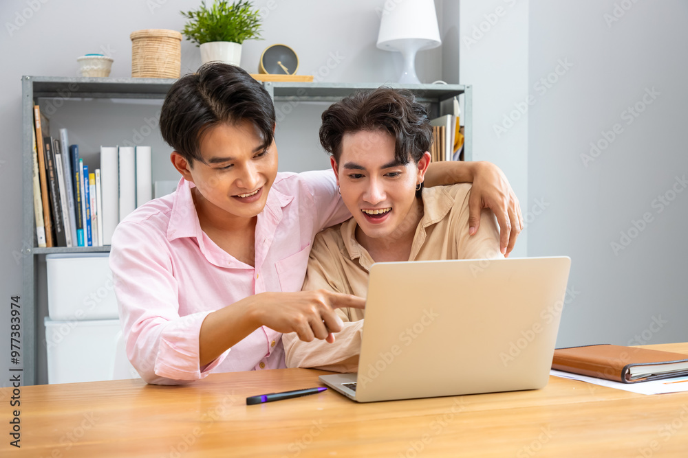 Happy two Asian men gay couple collaborating on laptop at home, working together in a relaxed atmosphere Happy two Asian men gay couple collaborating on laptop at home, working together in a relaxed atmosphere