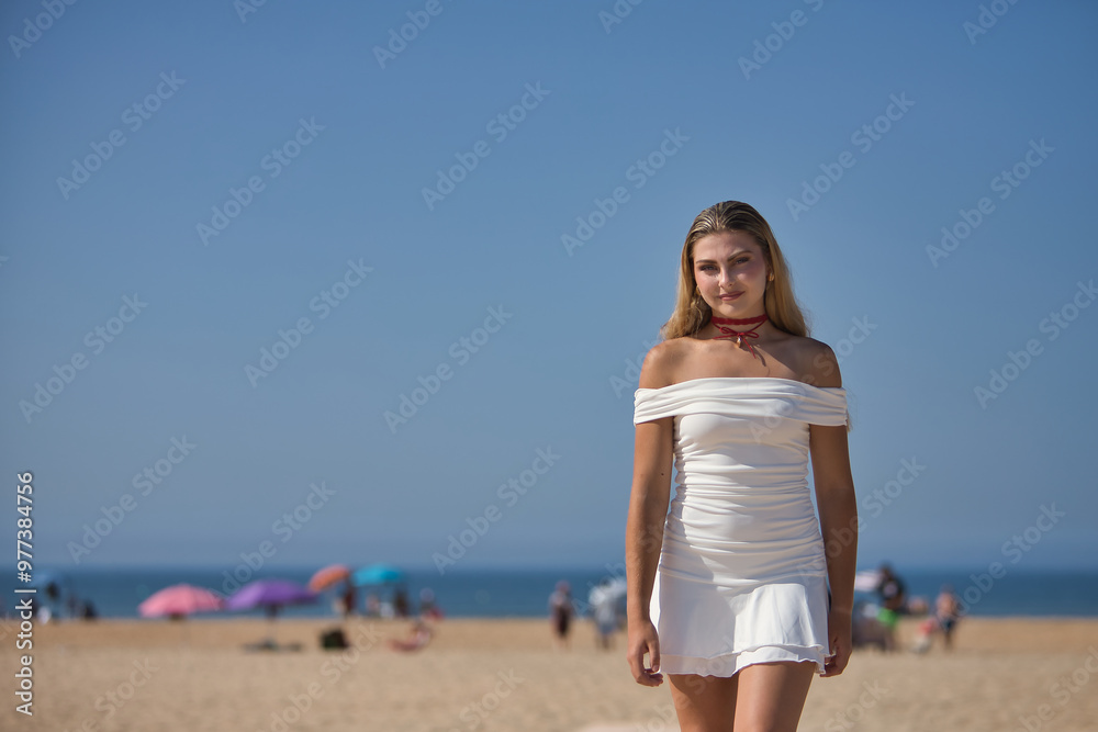 Young, beautiful, blonde woman in white dress, posing as a model on a wooden walkway on the beach with the sea in the background. Concept beauty, fashion, trend, femininity. Young, beautiful, blonde woman in white dress, posing as a model on a wooden walkway on the beach with the sea in the background. Concept beauty, fashion, trend, femininity.