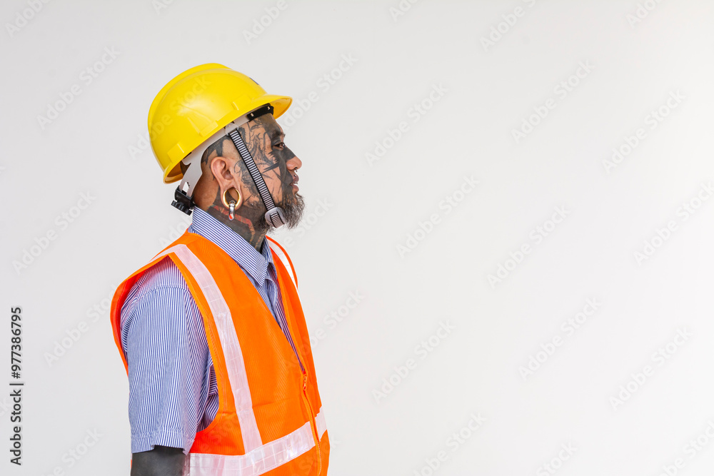 Side view of an unconventional looking engineer in a hard hat and vest. Full of face tattoos and piercings. Isolated on a white background. Side view of an unconventional looking engineer in a hard hat and vest. Full of face tattoos and piercings. Isolated on a white background.