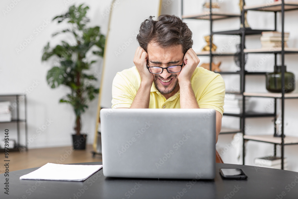 Upset freelancer working on laptop in his own office. Business crisis and problems concept Upset freelancer working on laptop in his own office. Business crisis and problems concept