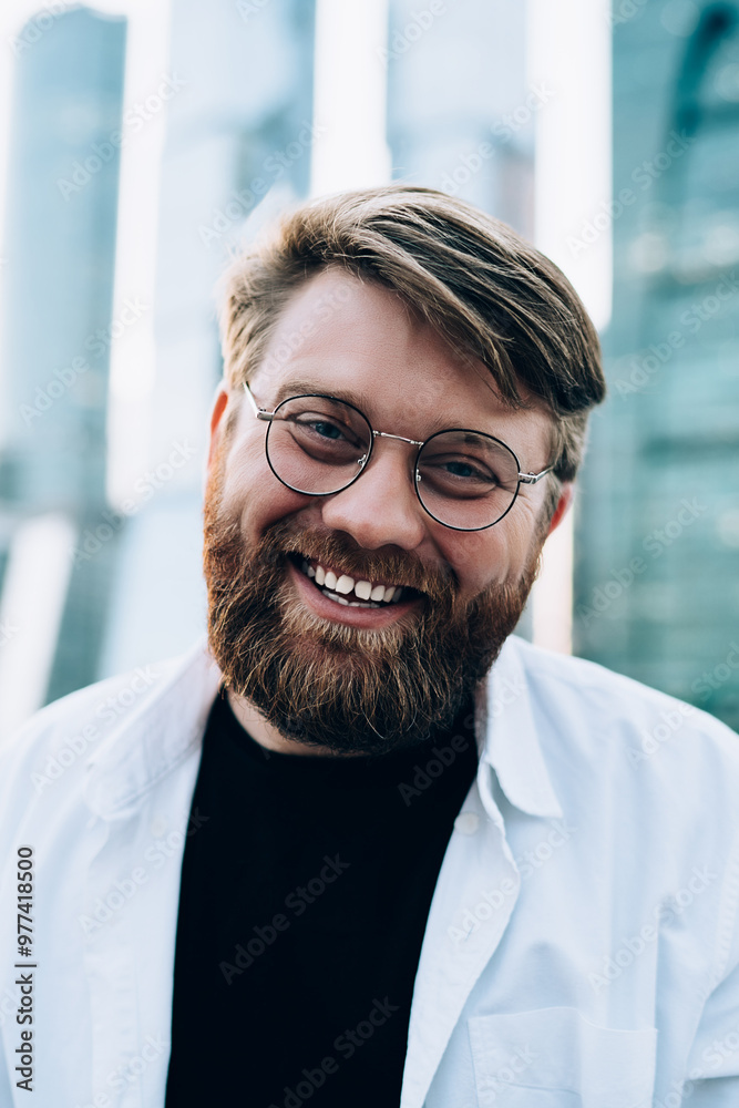 Close up portrait of cheerful Caucasian male in trendy optical spectacles for provide eyes protection smiling at camera during leisure time at city urban setting, happy man rejoicing at street Close up portrait of cheerful Caucasian male in trendy optical spectacles for provide eyes protection smiling at camera during leisure time at city urban setting, happy man rejoicing at street