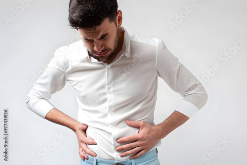 A man in a white shirt is clutching his stomach with a pained expression on his face. He appears distressed, isolated against a plain white background photo