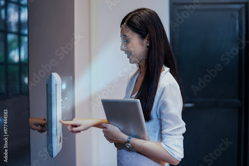Asian businesswoman scanning face ID to unlock door security with facial recognition technology for identification, with graphical technology illustration.