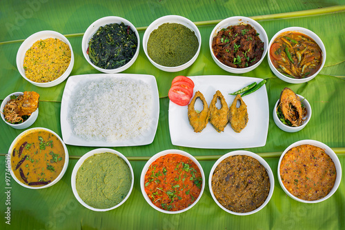 Traditional Bengali dishes such as bhorta, bhaji, fish curry, and vegetable curry are served in white ceramic pots and with Banana leaves. photo