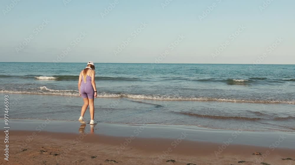 Young woman strolls along serene beach, enjoy calming ambiance of her summer getaway. Gentle waves and bright skies provide an ideal setting for relaxation and solitude