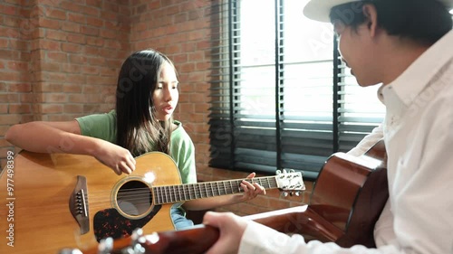 Young asian girl is learning how to play guitar from her teacher in the after school music class for education children skill and talent development