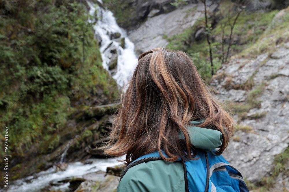 Naklejka premium Girl from behind admires the Lenteney Waterfall in La Salle in Aosta Valley, Italy.