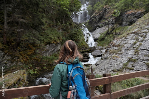 Girl from behind admires the Lenteney Waterfall in La Salle in Aosta Valley, Italy.