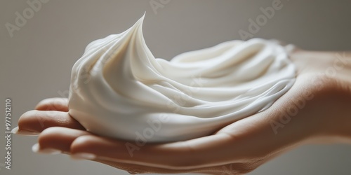 A close-up of whipped cream elegantly balanced in a hand, showcasing its smooth texture and creamy white color.