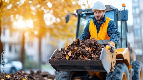 A construction worker wearing a safety vest and helmet operates heavy machinery loading a pile of dirt, highlighting labor and industriousness at a job site.