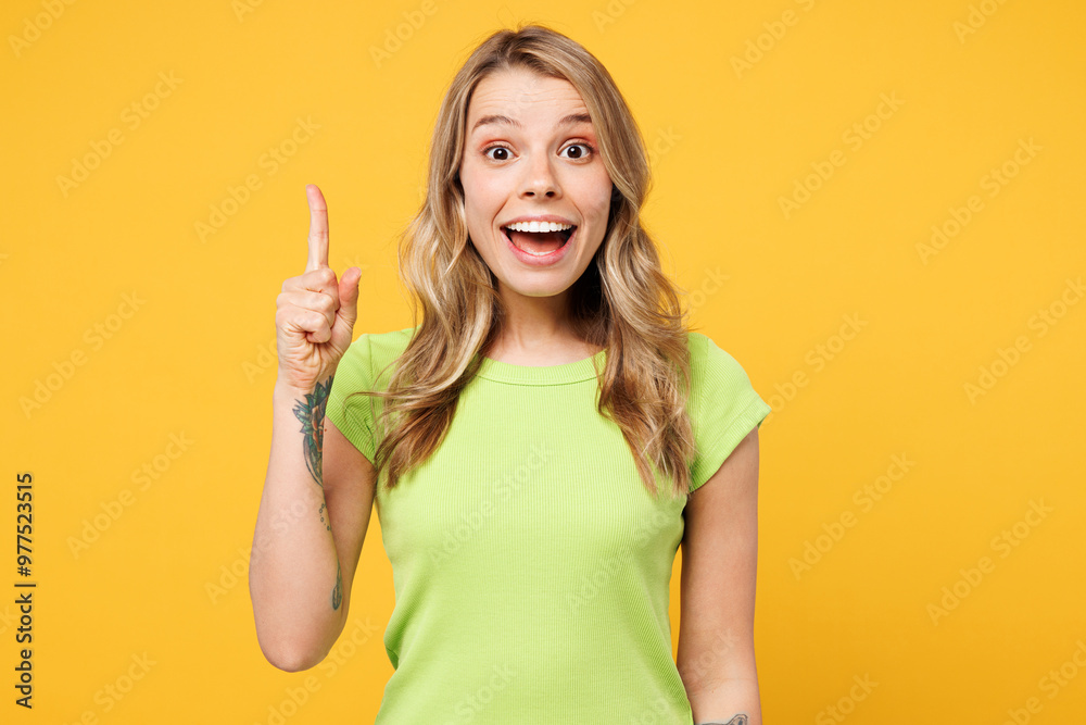 Young clever proactive happy blonde woman wear green t-shirt casual clothes holding index finger up with great new idea isolated on plain yellow orange background studio portrait. Lifestyle concept. Young clever proactive happy blonde woman wear green t-shirt casual clothes holding index finger up with great new idea isolated on plain yellow orange background studio portrait. Lifestyle concept.