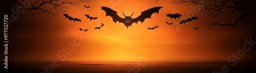 A haunting sunset scene with flying bats silhouetted against an orange sky, perfect for Halloween or spooky themes. photo