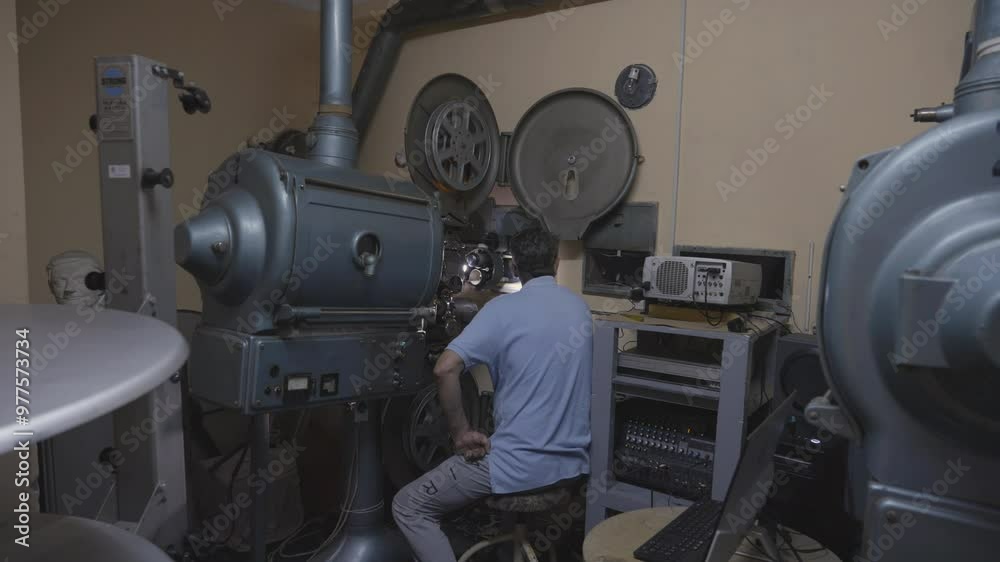 Film operator watching old cinema projector in action Film operator watching old cinema projector in action