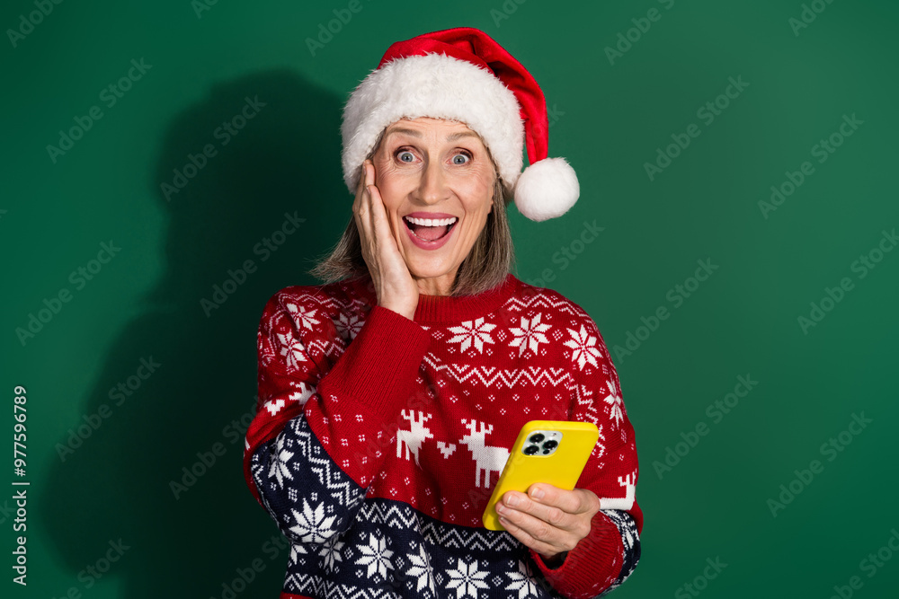 Photo of cheerful cute woman wear stylish red ugly clothes hold gadget wow news isolated on green color background Photo of cheerful cute woman wear stylish red ugly clothes hold gadget wow news isolated on green color background