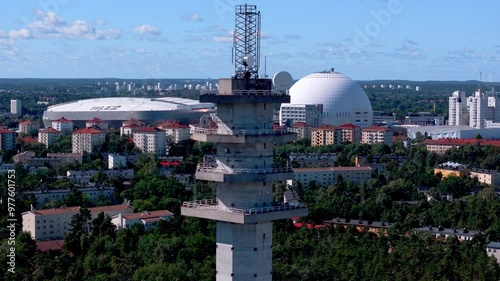 Aerial view of a concrete telecommunications tower overlooking the dense urban landscape of Stockholm, Sweden. The iconic Ericsson Globe and Tele2 arena stand out amidst the cityscape photo