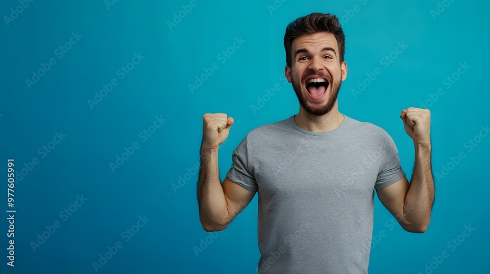 A young man with a beard in a grey t-shirt, exuberant with joy and excitement. A young man with a beard in a grey t-shirt, exuberant with joy and excitement.