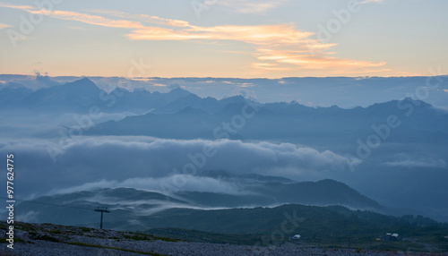 Sunset over the valley Rendena as seen from Passo del Groste. Mountain range Adamello-Presanella in background. Sunset clouds and sky. Vivid red sunset. Mist rising above the valley. Brenta Dolomites. photo