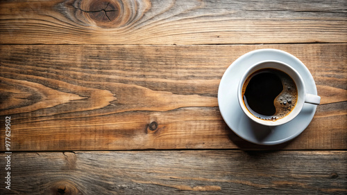 A top view of black hot coffee in white ceramic cup placed on rustic wooden table creates warm and inviting atmosphere