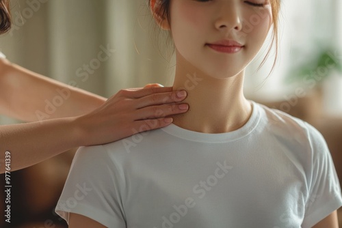 Japanese woman in casual clothes is receiving a neck massage from a physical therapist for chronic stiff neck, with the physical therapist's hands lightly holding her shoulders. photo