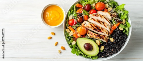 TopDown View of a Chicken and Black Rice Salad with Avocado and Dressing on White Wood