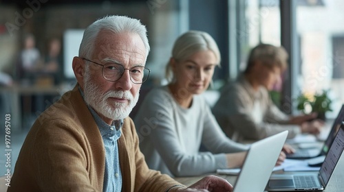 Senior entrepreneurs using digital devices for a startup project, grey-haired professionals working on a laptop, vibrant and diverse team of elderly businesspeople