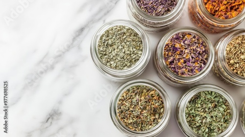 Top view of a variety of dried herbs in glass jars, placed on a marble countertop, dried herbs, herbal medicine and seasoning concept photo