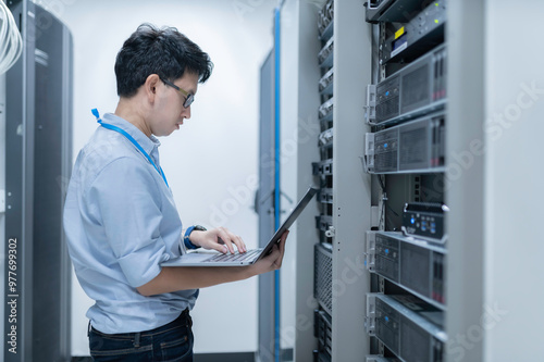 Computer engineer is setting up network in server room,Systems Maintenance Technician,Male engineer working in server room at modern data center