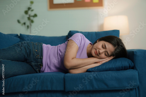 Young woman peacefully naps on a comfy sofa in her cozy living room, enjoying a moment of rest and tranquility at home