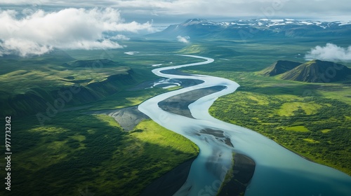 Obraz na płótnie An aerial view shows a winding river in Iceland, surrounded by lush valleys and rugged mountains. w salonie