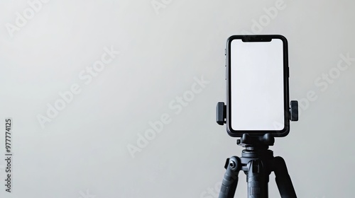 A smartphone with a blank display attached to a tripod, isolated against a white background