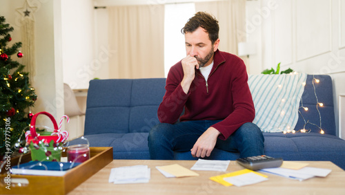 Foto Man anxiously bites his nails while tallying up his holiday spending at home