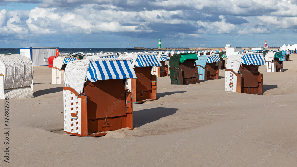 Φωτογραφία Strandkörbe am Strand von Rostock-Warnemünde in Mecklenburg-Vorpommern an der Ostsee Im Hintergrund die Leuchttürme (Molenfeuer) der Hafeneinfahrt