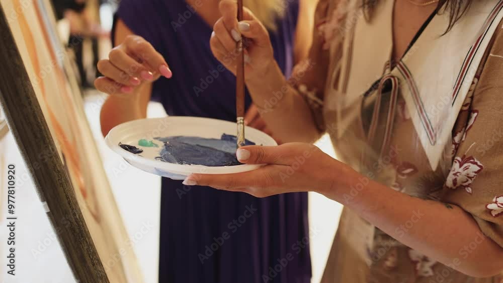 Process of drawing with brush, group class of talented students with painting easels and canvases during lesson of watercolour painting in auditorium, drawing class for adult artists in art school,