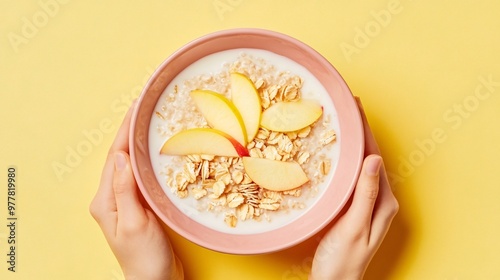 A bowl of milk-based bircher muesli with apple slices, isolated on a soft pastel yellow background for a bright and healthy look photo