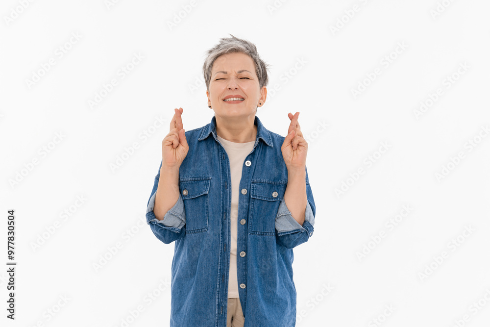 Photo portrait of attractive mature adult lady woman with short grey hairstyle dressed casual outfit denim shirt crossed fingers hope wish closed eyes standing isolated on white background Photo portrait of attractive mature adult lady woman with short grey hairstyle dressed casual outfit denim shirt crossed fingers hope wish closed eyes standing isolated on white background