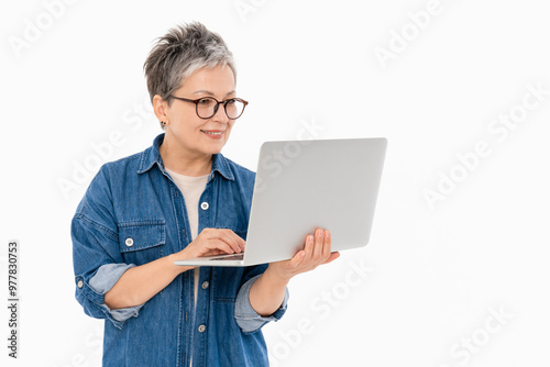 Smiling mature adult woman using holding laptop pc computer, working online remotely, communication with family, looking at screen isolated on white color background studio portrait.