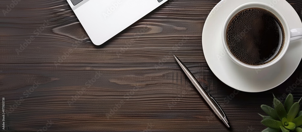 Black coffee on the office desk alongside a computer and silver pen Business desk seen from above with copyspace concept