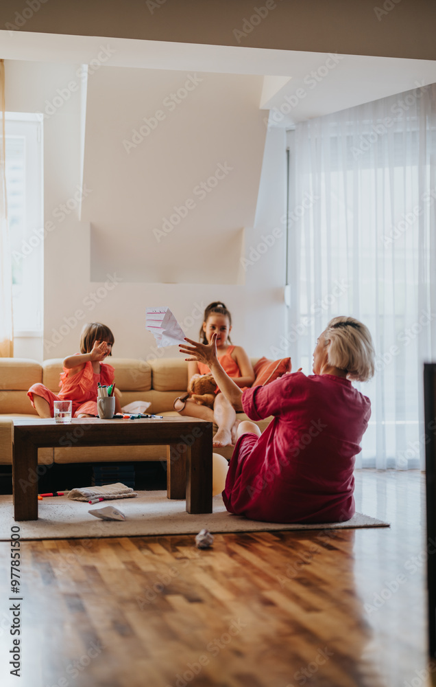 Three generations engage in playful activities in a bright and cozy living room, showcasing family bonding and creativity. Three generations engage in playful activities in a bright and cozy living room, showcasing family bonding and creativity.