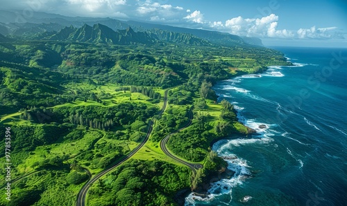 Aerial view of a road winding through green trees near the ocean.
