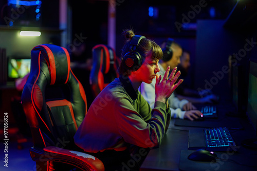 Fotografie Tense gamer girl sitting in game room in uptight situation in game
