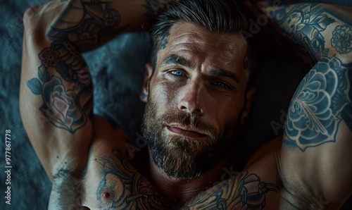 Muscular tattooed man lying on his back with his hands behind head