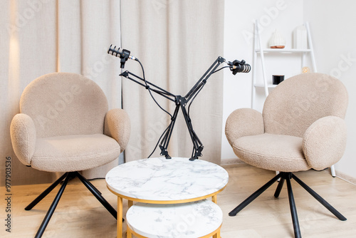 Cozy living room with two chairs and a mic setup for a casual podcast recording session in a modern apartment