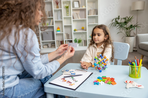 Cute girl having an educational session with a speech therapist and looking involved