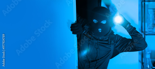 Canvastavla A person dressed in dark clothing and a ski mask peers into a dimly lit room while holding a flashlight, suggesting an illicit entry at night