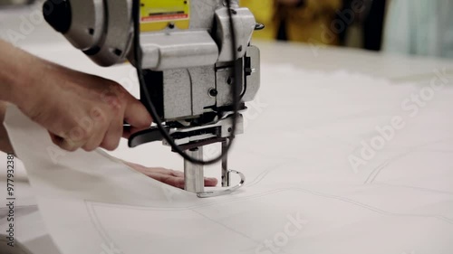 A man makes clothing patterns with a cutter knife in a factory. Cutting room, cutting cloth tailoring knife.