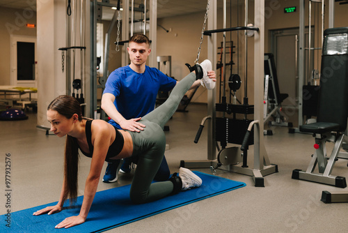 Preventing rheumatoid diseases with kinesiotherapy. Kinesiologist is assisting his female patient during back rehabilitation exercise. photo