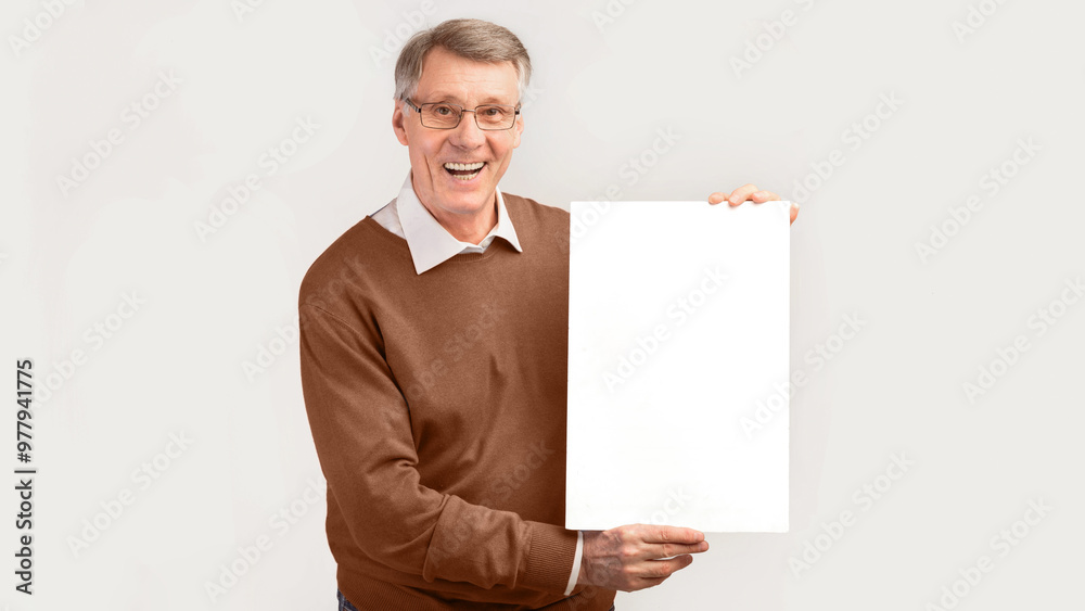 Smiling Senior Man Holding Blank White Poster Standing Over Studio Background. Mockup, Panorama Smiling Senior Man Holding Blank White Poster Standing Over Studio Background. Mockup, Panorama